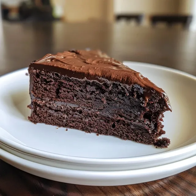 Side view of a decadent vegan gluten-free chocolate cake featuring a smooth chocolate topping.