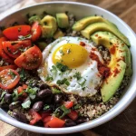 A side view of a nutritious breakfast bowl filled with quinoa, eggs, avocado, and diced tomatoes.
