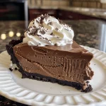 A mouthwatering side angle of a chocolate cheesecake icebox pie, featuring a smooth chocolate topping.