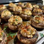 Juicy stuffed baby bell mushrooms garnished with chopped parsley on a wooden table.