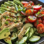 Side view of a colorful salad featuring diced chicken, ripe avocados, and halved cherry tomatoes.