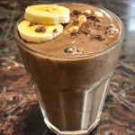 A delicious-looking banana chocolate smoothie with a hint of cocoa, captured from the side.