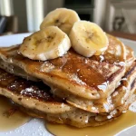 Juicy banana oat protein pancakes served on a white plate, showing their texture.
