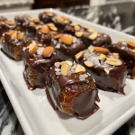 Juicy chocolate-dipped dates with a creamy almond butter filling, showcasing a glossy chocolate exterior.