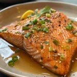 Salmon fillet steaming with colorful garnishes, showcasing a healthy meal.