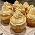 A close-up side view of a delicious vanilla cupcake with creamy frosting.