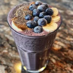 Close-up of a creamy banana blueberry peanut butter smoothie in a glass.