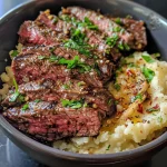 Juicy beef cubes in garlic butter over a bed of white rice in a bowl.