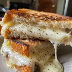 Side view of a juicy grilled cheese sandwich with melted cheese oozing out.
