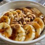 Bowl filled with caramelized banana, creamy yogurt, and nuts arranged attractively.