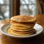 Fluffy mini pancakes layered with strawberries and Nutella, showcasing a mouthwatering side view.
