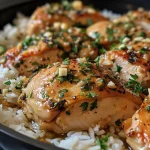 A detailed shot of One-Pot Garlic Butter Chicken with glistening rice and herbs, served in a deep dish.