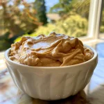 Creamy peanut butter yogurt dip in a bowl, accompanied by vibrant red apple slices.