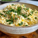 Side view of creamy scrambled eggs garnished with parsley on a plate.