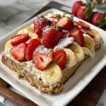A deliciously rich strawberry banana cake with vibrant strawberry slices on top.