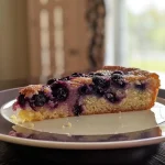 ['Close-up of a slice of blueberry yogurt cake with fresh blueberries on top.', 'Side view of blueberry yogurt cake, showcasing its moist texture and blueberry filling.', 'A delicious slice of blueberry yogurt cake with powdered sugar dusting, placed on a white plate.', 'Juicy blueberry yogurt cake slice displayed on a rustic wooden table.']