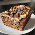 ['Close-up of mini banana bread slice with chocolate chips and walnuts.', 'Side view of a moist mini banana bread showcasing its texture and ingredients.', 'Juicy mini banana bread on a plate with visible chocolate chips and walnuts.', 'Detailed view of a mini banana bread slice, highlighting its soft interior and toppings.']