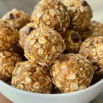 ['A close-up side view of Peanut Butter Oat Balls stacked on a rustic wooden surface.', 'Juicy and delicious Peanut Butter Oat Balls displayed in a light, natural setting.', 'A detailed shot of round Peanut Butter Oat Balls with visible oats and chocolate chips.', 'A side view of freshly made Peanut Butter Oat Balls on a wooden board, highlighting their texture.']