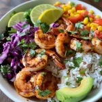 ['A vibrant shrimp taco rice bowl with colorful toppings, viewed from the side.', 'Close-up of a juicy shrimp taco rice bowl featuring fresh ingredients and garnishes.', 'A detailed look at a shrimp taco rice bowl with shrimp, avocado, and cherry tomatoes.', 'Side view of a delicious shrimp taco rice bowl, showcasing its colorful components.']