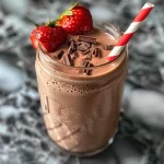 ['Close-up view of a vibrant strawberry chocolate smoothie in a glass.', 'Side view of a creamy strawberry chocolate smoothie with fresh strawberries on the rim.', 'Juicy strawberry chocolate smoothie topped with strawberries, set against a wooden background.', 'Rich, thick strawberry chocolate smoothie displaying a luscious texture in a clear glass.']