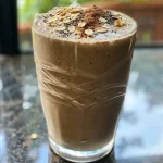 ['Close-up side view of a creamy SunButter Breakfast Shake, showcasing its texture and color.', 'A vibrant, delicious-looking SunButter Breakfast Shake in a glass, with a focus on ingredients like chia seeds and oats.', 'Side view of a SunButter Breakfast Shake, creamy and inviting, set against a simple background.', 'Close-up of a thick, homemade SunButter Breakfast Shake with visible chunks of banana and chia seeds.']