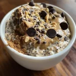 ['Close-up of creamy chocolate chip cookie dough overnight oats in a clear jar.', 'Side view of a jar filled with chocolate chip cookie dough overnight oats, displaying chocolate chips on top.', 'Vibrant layer of chocolate chip cookie dough overnight oats with a smooth texture.', 'Delicious chocolate chip cookie dough overnight oats in a transparent container, showcasing oats and chocolate chips.']