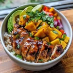 ['A vibrant chicken mango rice bowl featuring juicy chicken, diced mango, and fresh vegetables.', 'Close-up of a colorful rice bowl with chicken, mango, and garnishes, served in a white bowl.', 'A delicious bowl filled with chicken, mango, rice, and assorted veggies, showcasing bright colors.', 'A side view of a chicken mango rice bowl, highlighting the juicy chicken and fresh mango pieces.']