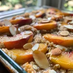 ['A close-up view of a delicious peach cobbler topped with almond slices and coconut flakes.', 'Juicy slices of peaches in a baked cobbler with a golden crust and sprinkled with oats and almonds.', 'High-protein peach cobbler served in a dish, featuring fresh peach slices and a crunchy topping.', 'A side view of a peach cobbler accented with cinnamon, almond slices, and a scoop of Greek yogurt.']