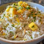['Close-up view of a bowl of Mango Lime Rice with coconut flakes and cilantro.', 'Side photograph of vibrant Mango Lime Rice garnished with fresh cilantro and toasted coconut.', 'Juicy Mango Lime Rice in a bowl, showcasing the colorful mango pieces and coconut flakes.', 'Detail shot of Mango Lime Rice highlighting the bright colors of mango, lime, and coconut.']