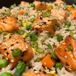 ['Close-up view of a vibrant bowl of salmon fried rice with colorful vegetables.', 'A side shot of delicious salmon fried rice, showcasing juicy salmon pieces and peas.', 'Close-up image of salmon fried rice, featuring onions, carrots, and a sprinkle of green onions.', 'Detailed view of cooked salmon fried rice, highlighting the texture and mix of ingredients.']
