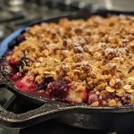['Close-up view of a warm Skillet Berry Crisp with a golden-brown topping.', 'Side view of a bubbling Skillet Berry Crisp filled with assorted berries.', 'Juicy Skillet Berry Crisp served in a cast-iron skillet, showcasing its crispy topping.', 'Delicious Skillet Berry Crisp with melted butter and fresh berries peeking through.']