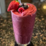 ['Close-up view of a vibrant Summer Berry Smoothie in a glass with fresh berries on top.', 'Side view of a delicious berry smoothie, showcasing its thick texture and colorful ingredients.', 'Juicy Summer Berry Smoothie with a mix of strawberries, blueberries, and raspberries in a clear glass.', 'Refreshing smoothie featuring strawberries and blueberries, ready to be enjoyed on a sunny day.']